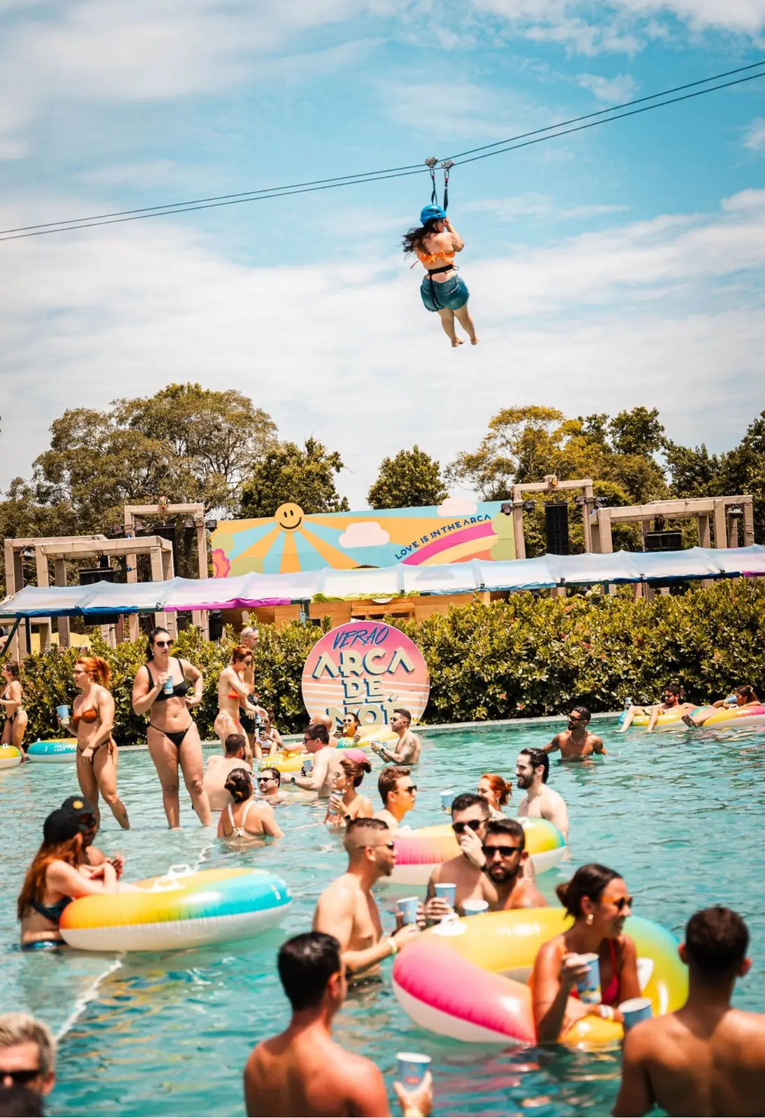 Pessoa em tirolesa sobrevoando festa em piscina