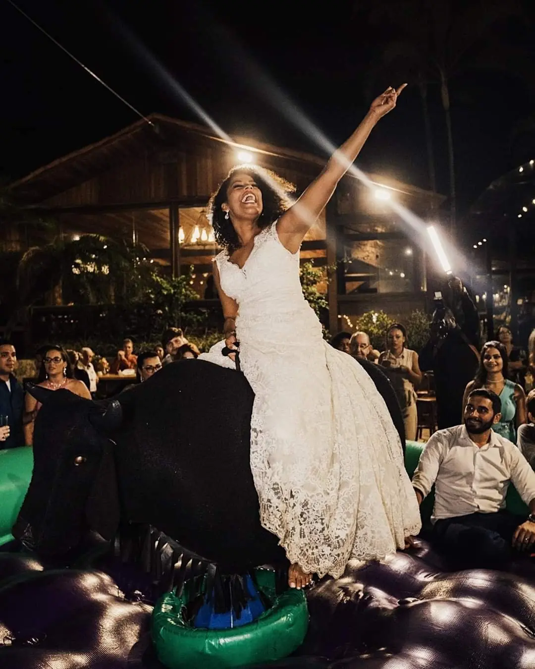 Noiva sorrindo em cima do touro mecânico durante a festa